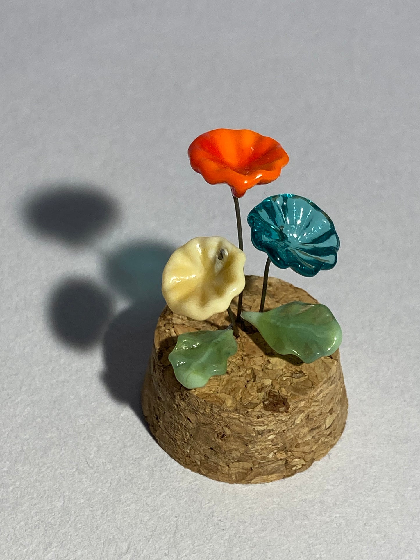 Fleurs bleues, blanches et rouges en verre sous cloches